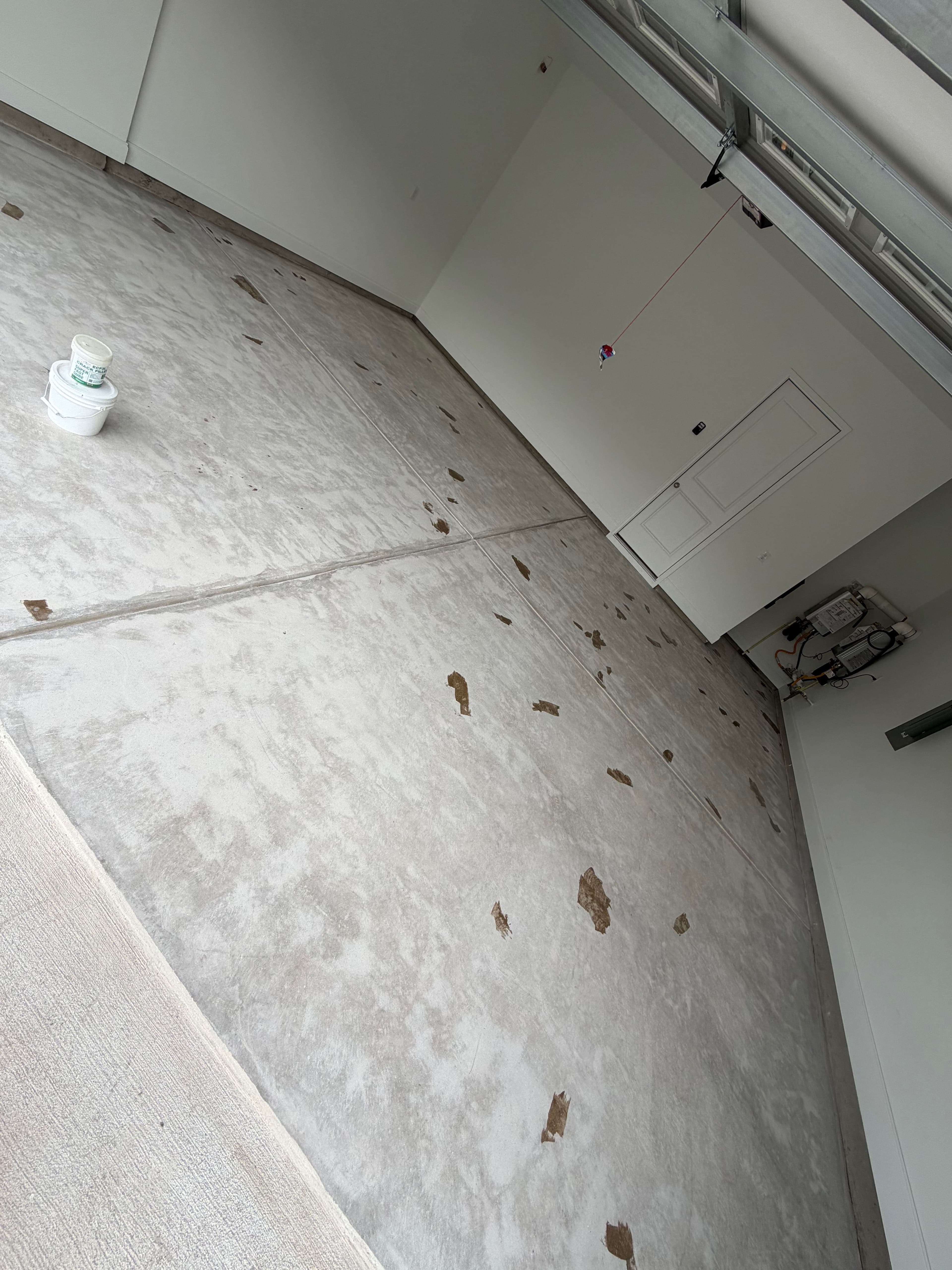 Empty garage with a concrete floor showing wear and a paint bucket in the corner.